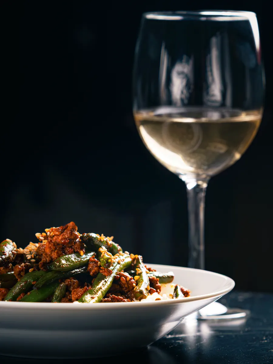 Glass of white wine behind a plated dish, Aki food photography